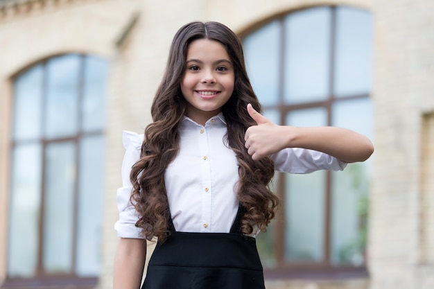 Soyez le meilleur possible. Un enfant heureux montre son pouce levé à l'extérieur. Regard d'école. Retour à la mode scolaire. Enseignement primaire. 1er septembre. Journée du savoir. Bravo si vous approuvez.