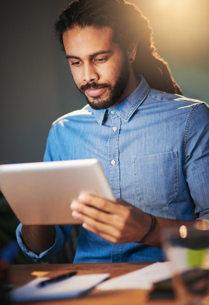 Soyez persistant dans votre recherche du succès Photo recadrée d'un jeune designer travaillant tard sur une tablette numérique dans un bureau