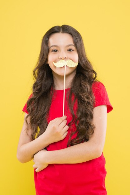 Soyons drôles éléments de fête enfance heureuse petit enfant fond jaune enfant joyeux avec de beaux cheveux longs petite beauté fête d'anniversaire temps souriant petite fille fête moustache