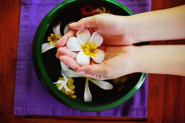 spa et beauté main féminine et fleur dans l'eau