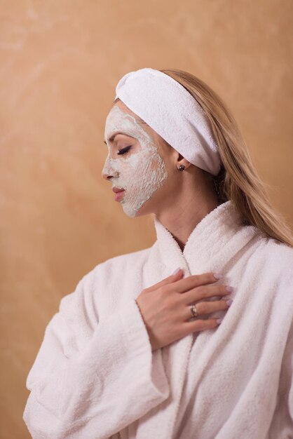Spa femme appliquant un masque facial soins de beauté Portrait en gros plan d'une belle fille avec une serviette sur la tête appliquant un masque facial
