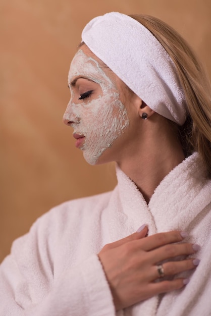 Spa femme appliquant un masque facial soins de beauté Portrait en gros plan d'une belle fille avec une serviette sur la tête appliquant un masque facial