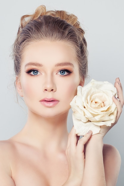 Spa femme aux cheveux blonds et fleur de rose blanche. Concept de soins de la peau