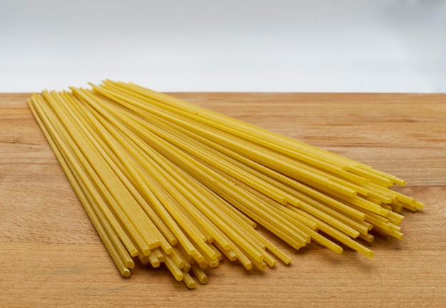 Spaghetti alla chitarra pâtes italiennes fraîches sur une table en bois à fond blanc