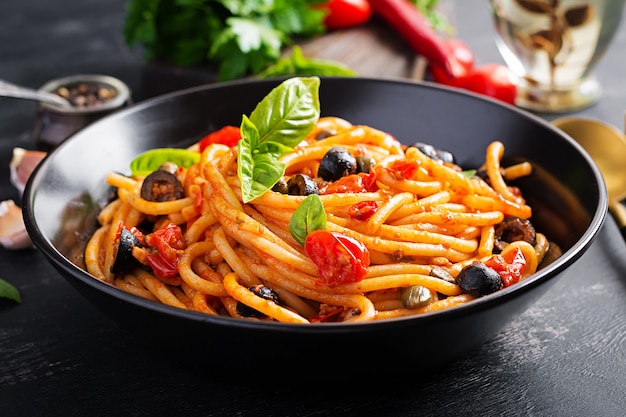 Spaghetti alla puttanesca - plat de pâtes italiennes aux tomates, olives noires, câpres, anchois et basilic.