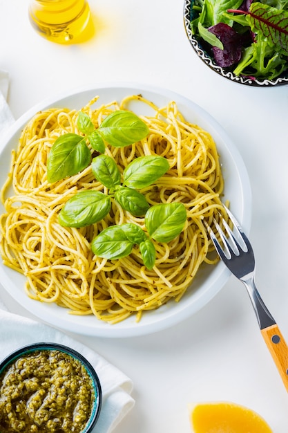 Spaghetti au pesto et basilic sur fond blanc