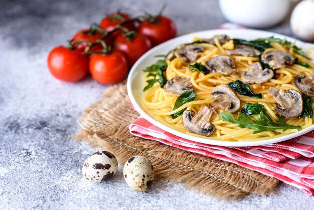 Spaghetti aux champignons, fromage, épinards, rukkola et tomates cerises. Plat italien, culture méditerranéenne