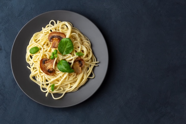 Spaghetti aux champignons et sauce crémeuse à l'ail sur un espace sombre