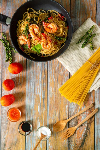 Spaghetti aux crevettes et légumes sur fond de bois