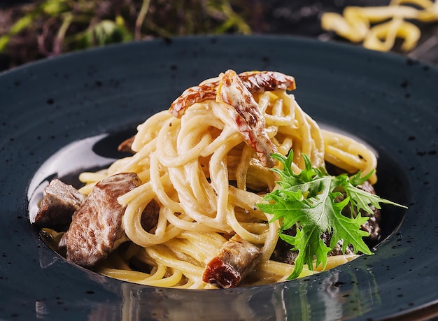 Spaghetti aux morceaux de veau et roquette sur assiette