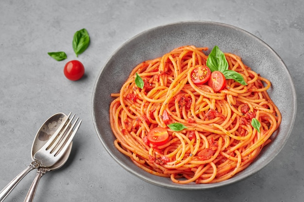 Photo spaghetti aux tomates dans un bol gris sur une surface en béton. les pâtes à la sauce tomate sont un plat classique de la cuisine italienne. nourriture italienne