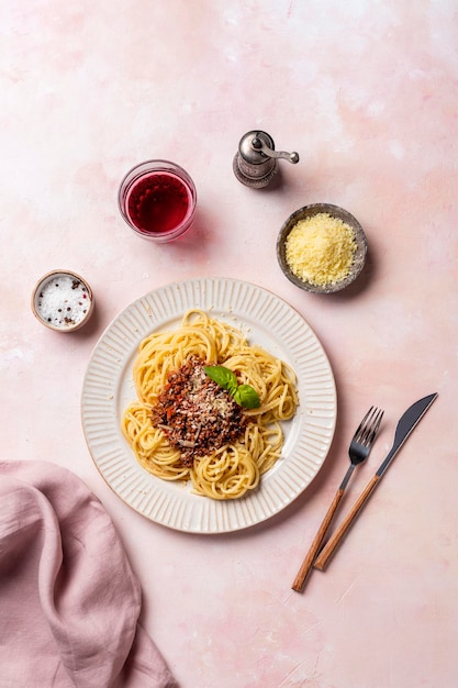 Spaghetti bolognaise dans une assiette blanche sur fond rose clair Vue d'en haut