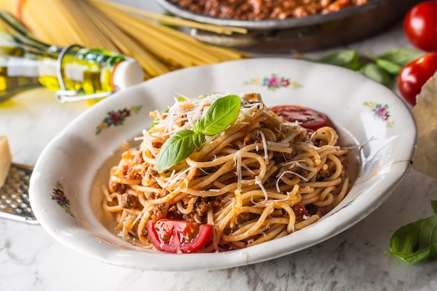 Spaghetti bolognaise avec ingrédients basilic tomates parmesan et huile d'olive.