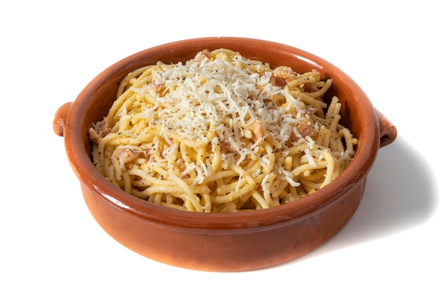 Spaghetti carbonara au fromage râpé, servi dans un bol en argile. Isolé sur fond blanc.