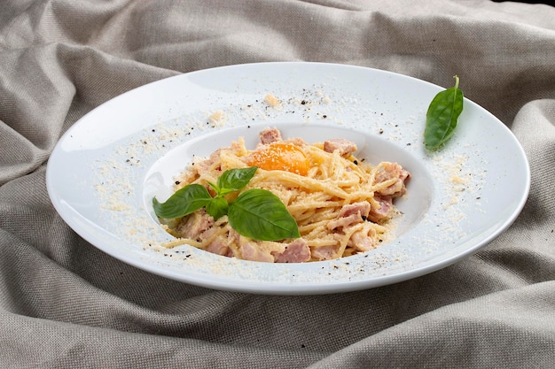 Spaghetti Carbonara sur plaque blanche sur fond textile