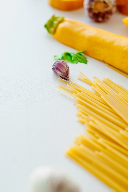 Spaghetti à la courgette jaune, tomate, ail, champignon, persil sur fond blanc plat poser