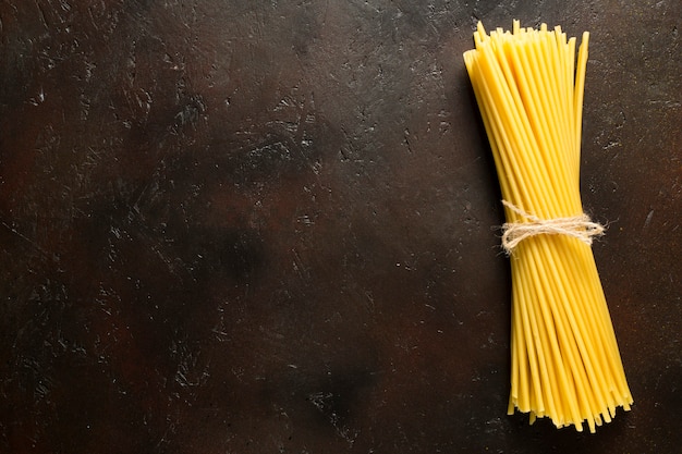 Spaghetti cru attaché avec une corde sur une surface brune