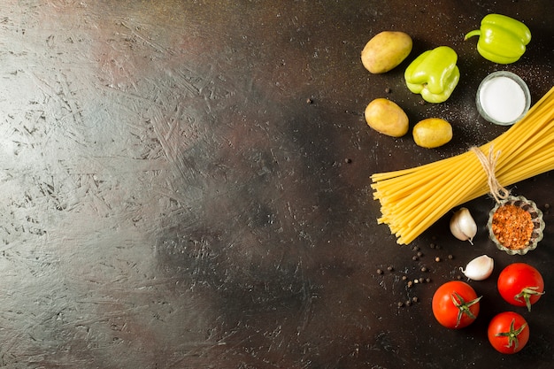 Spaghetti cru avec des ingrédients sur le fond marron