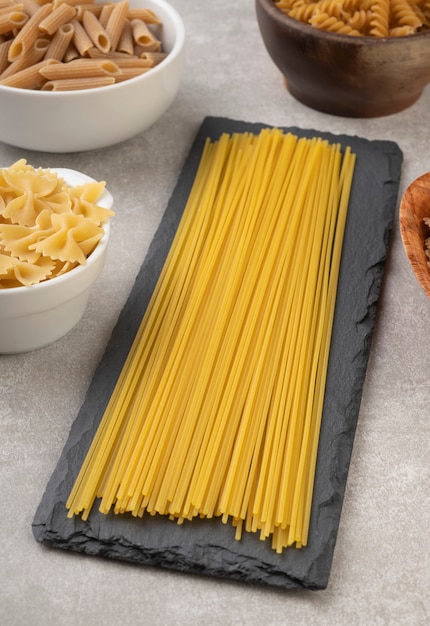 Spaghetti, farfalle, fusilli et pâtes penne sur un comptoir en béton.