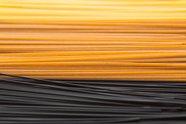 Spaghetti long jaune sur fond gris. Pâtes italiennes de différentes variétés de blé et de différentes couleurs. Vue de dessus des spaghettis crus, concept de plat de fond de nourriture.