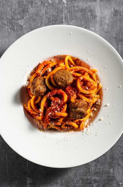 Spaghetti maison avec sauce tomate parmesan et boulettes de viande sur fond sombre