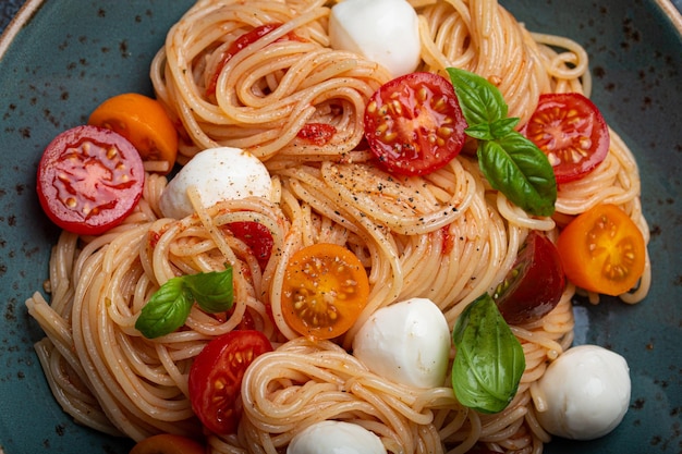 Spaghetti à la mozzarella tomates cerises colorées basilic frais sur plaque en céramique