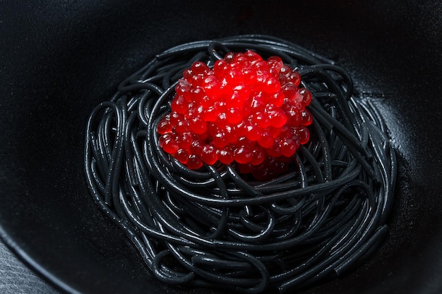 Spaghetti noir avec pâtes au caviar rouge sur fond noir vue de dessus aucun peuple