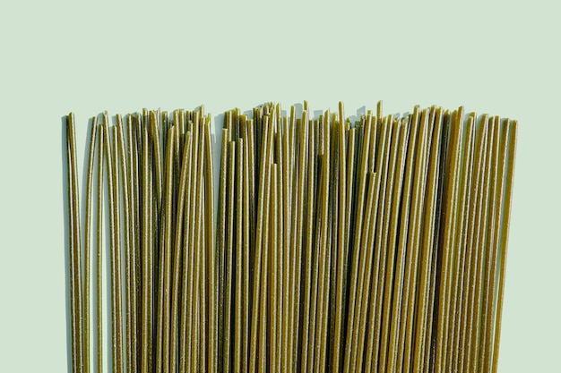 Spaghetti de nouilles de pâtes crues Couleur verte spiruline épinards chlorellal Nourriture végétalienne Soba non cuit sur fond vert clair avec espace pour le texte