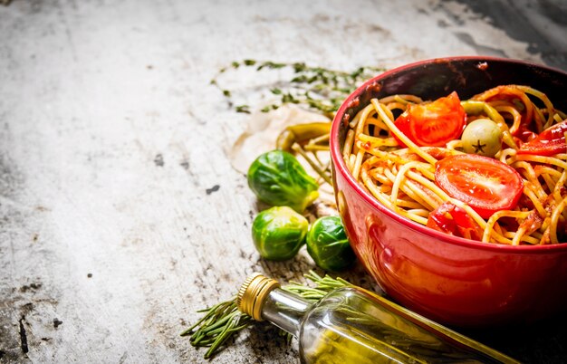 Spaghetti à la pâte de tomates, herbes et poivrons. Sur table rustique. Espace libre pour le texte.