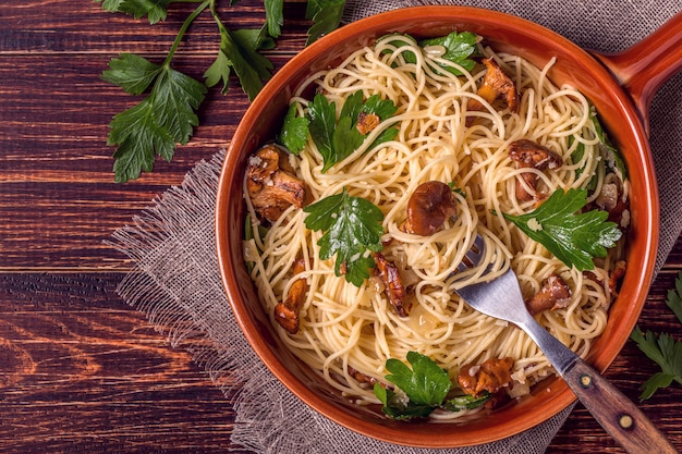 Spaghetti de pâtes aux girolles sur table en bois.