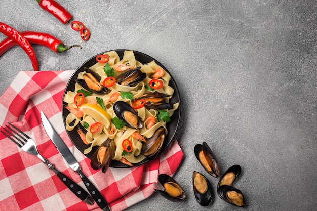 Spaghetti de pâtes faites maison avec moules, piment et persil sur fond de pierre. repas de fruits de mer