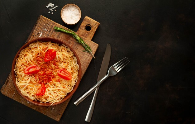 Spaghetti de pâtes italiennes appétissantes avec sauce tomate, parmesan sur une plaque, planche à découper sur un fond de pierre. Vue d'en-haut