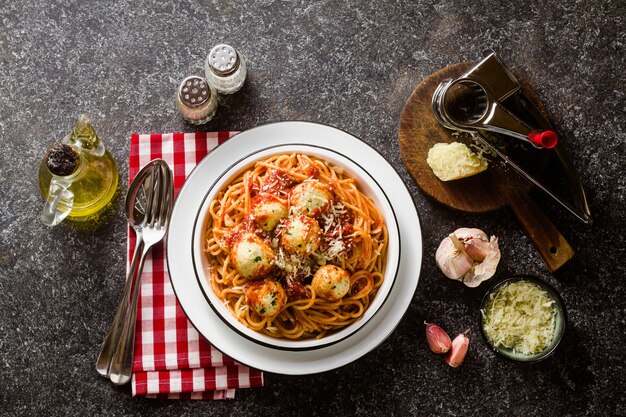 Spaghetti de pâtes italiennes avec des boules de ricotta à la sauce tomate sur la table avec du parmesan.