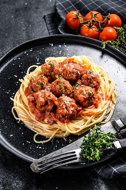 Spaghetti de pâtes italiennes à la sauce tomate et boulettes de viande. Fond noir. Vue de dessus