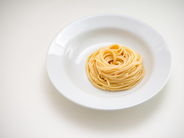 Spaghetti, pâtes sur plaque sur fond blanc