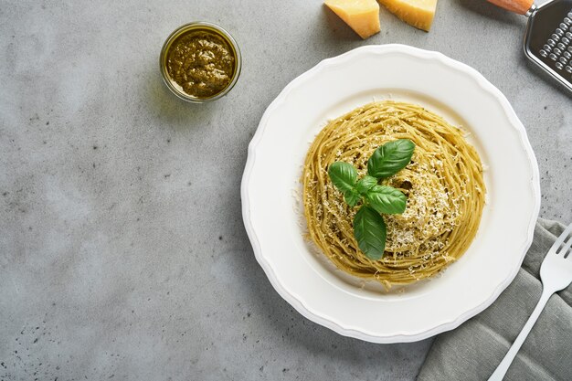 Spaghetti de pâtes avec sauce pesto et feuilles de basilic frais dans un bol blanc