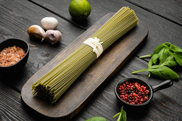 Spaghetti de pâtes vertes non cuites italiennes sur fond de table en bois noir