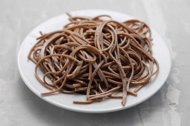 Spaghetti de sarrasin sur plaque blanche sur fond en céramique