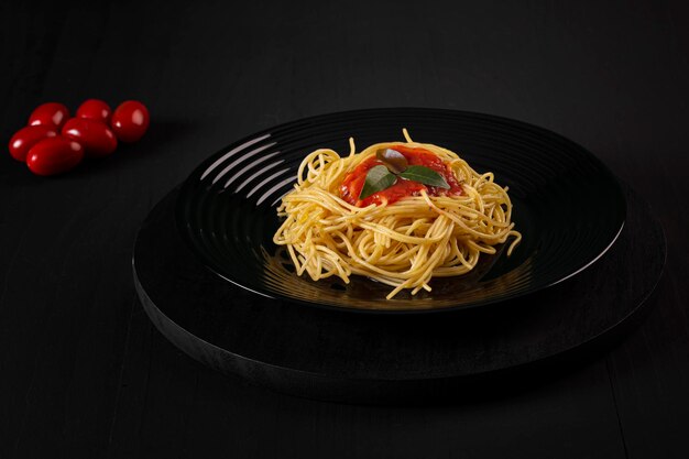 Spaghetti avec sauce sur une plaque noire dans une photo de studio plus sombre