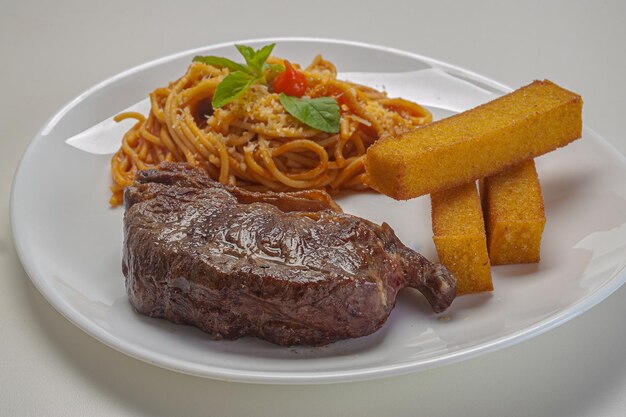 Spaghetti à la sauce sugo avec parmesan servi avec filet et polenta frite