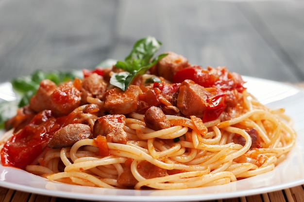 Spaghetti à la sauce tomate au poulet, tomates, décoré de persil sur une table en bois