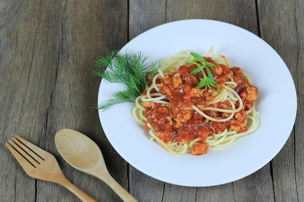 Spaghetti à la sauce tomate dans un plat blanc sur fond de parquet
