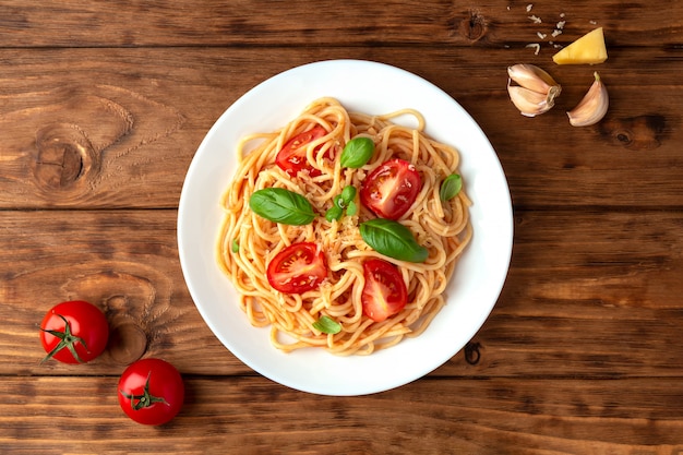 Photo spaghetti à la sauce tomate avec du fromage et du basilic sur un espace en bois