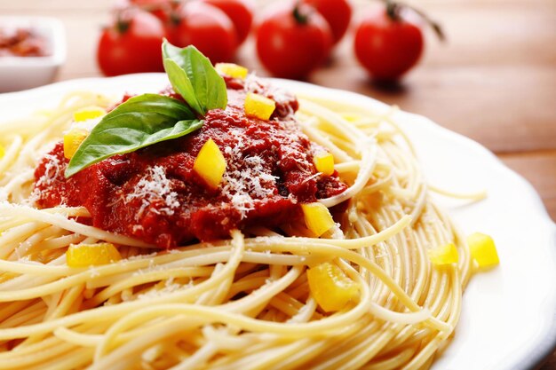 Spaghetti à la sauce tomate paprika et fromage sur plaque blanche sur fond de bois de couleur