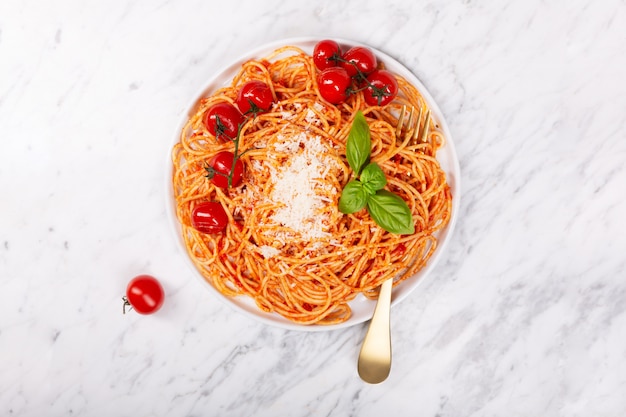 Spaghetti à la sauce tomate et tomates cerises au basilic sur une table en pierre blanche