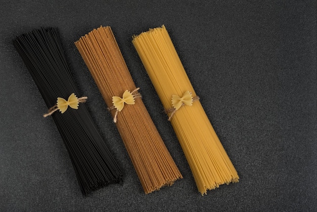 Spaghetti sec brun noir et jaune sur fond gris ingrédients italiens