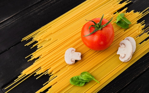 Spaghetti à la tomate, aux champignons et aux épinards sur fond noir. Concept d'alimentation saine.