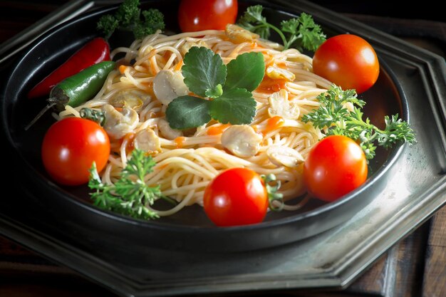 Des spaghettis bouillis avec des assaisonnements et des légumes sur un vieux fond