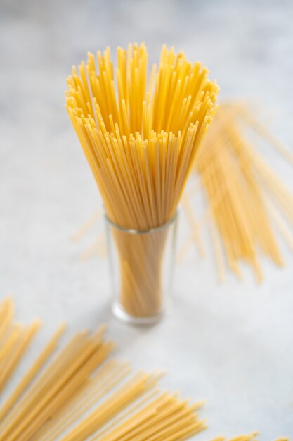 Spaghettis longs jaunes en verre sur fond blanc.