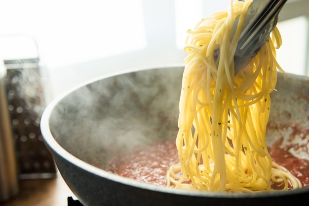 spaghettis mis dans la sauce bolognaise chaude dans la casserole